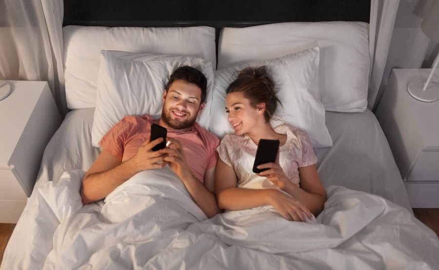 happy-couple-using-smartphones-bed-night