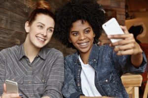 stylish-african-american-girl-with-afro-haircut-holding-mobile-taking-selfie